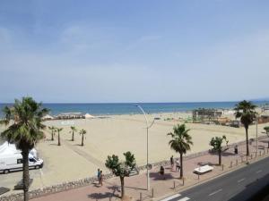 a beach with palm trees and a white car on a street at Appartement face Mer, idéal famille 6NOUM12 sea view 2 bedrooms apartment in Canet-en-Roussillon