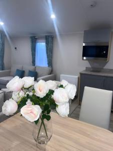 a vase filled with white roses sitting on a table at Brand New Modern Holiday Home - Haven The Orchards Holiday Park in Saint Osyth