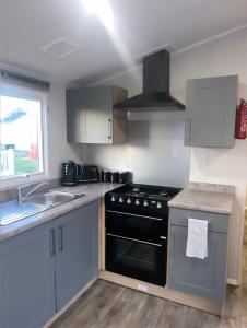 a kitchen with a stove and a sink at Brand New Modern Holiday Home - Haven The Orchards Holiday Park in Saint Osyth