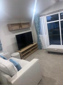 a living room with a couch and a flat screen tv at Brand New Modern Holiday Home - Haven The Orchards Holiday Park in Saint Osyth