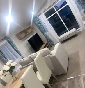 a living room with a couch and chairs and a window at Brand New Modern Holiday Home - Haven The Orchards Holiday Park in Saint Osyth