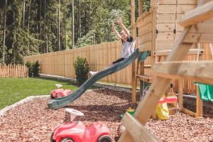 a boy on a slide in a playground at Apartments Silva Living in San Giovanni in Val Aurina