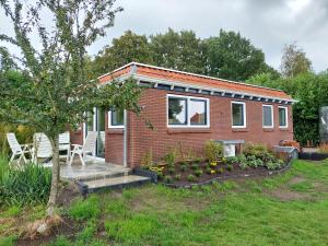 een klein rood bakstenen huis met twee stoelen en een boom bij Huisjedelinde in Wolvega