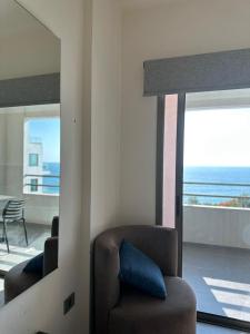 a living room with a chair and a view of the ocean at Le Six Hotel And Resort in Batroûn