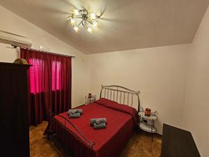 een slaapkamer met een rood bed en 2 handdoeken erop bij Case Magliolo in Cefalù