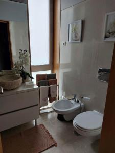 uma casa de banho com um WC, um lavatório e um espelho. em Appartement en face de la mer em Azurara