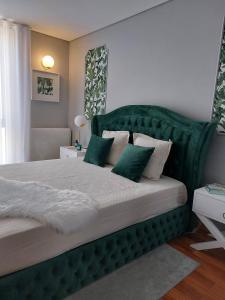 sypialnia z dużym zielonym łóżkiem z zielonymi poduszkami w obiekcie Appartement en face de la mer w mieście Azurara