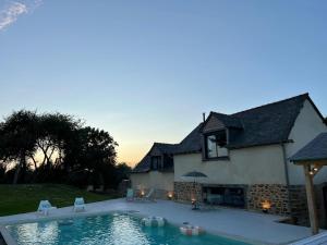 a house with a swimming pool in front of a house at Le Logis de la Lettre in Tinténiac