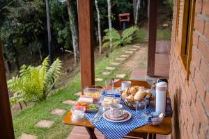 a table with a blue checkered table cloth with food on it at Chalés Terra dos Sonhos - Monte Verde in Monte Verde