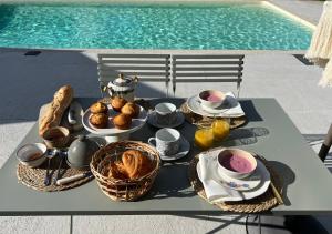 una mesa con desayuno junto a una piscina en Le Logis de la Lettre, en Tinténiac