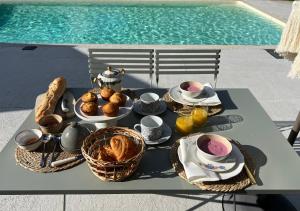 - une table avec de la nourriture pour le petit-déjeuner à côté de la piscine dans l'établissement Le Logis de la Lettre, à Tinténiac