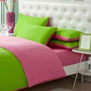 a bed with pink and green pillows and a table at Apartments Slavica Trogir in Trogir