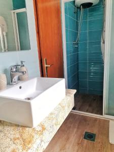 ein Badezimmer mit einem weißen Waschbecken und einer Dusche in der Unterkunft Guest House Kormilo in Ston