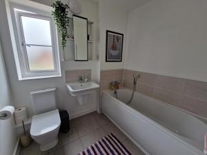 a bathroom with a tub and a toilet and a sink at Spacious 3 bedroom family home in Shinfield