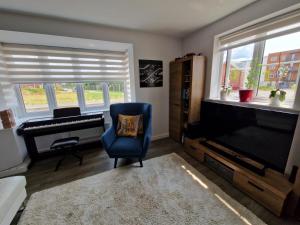a living room with a tv and a chair and a piano at Spacious 3 bedroom family home in Shinfield