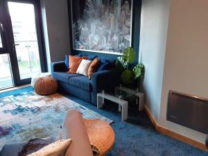 a living room with a blue couch and a tv at Northern Lights Apartment in Saltaire