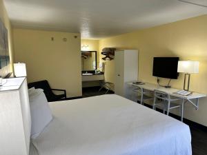 a bedroom with a white bed and a television at Seven Gables Inn in Branson