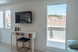 Zimmer mit einem Schreibtisch, einem TV und einem Fenster in der Unterkunft Apartamentos La Moneda in Burgos