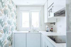 a kitchen with white cabinets and a floral wallpaper at Apartamentos La Moneda in Burgos +47 photos
