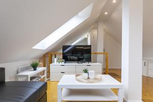 ein Wohnzimmer mit einem weißen Tisch und einem TV in der Unterkunft Attic Apartment with Peaceful view + Parking in Prag
