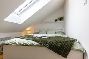 ein weißes Schlafzimmer mit einem Bett und grünen Decken in der Unterkunft Attic Apartment with Peaceful view + Parking in Prag