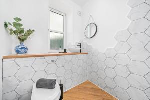 uma casa de banho com azulejos hexagonais brancos e um banco em Stylish 4 Bed-Town Centre em Galashiels