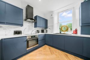 uma cozinha com armários azuis e uma janela em Stylish 4 Bed-Town Centre em Galashiels