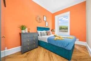 an orange bedroom with a bed and a window at Stylish 4 Bed-Town Centre in Galashiels