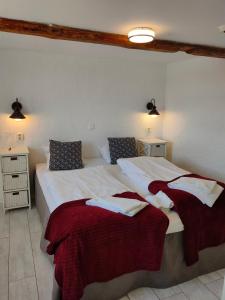 1 dormitorio con 2 camas y mantas rojas y blancas en Vingården i Arild, en Arild