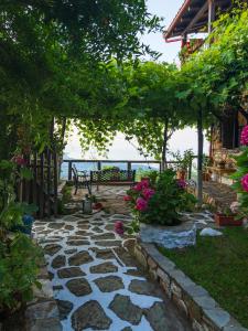 a garden with a stone walkway with a bench and flowers at Guesthouse Oneiro in Palaios Panteleimon