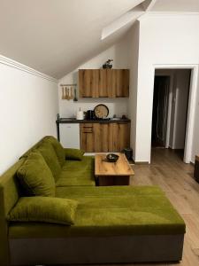 a living room with a green couch and a table at Guest Radic Apartments in Palić
