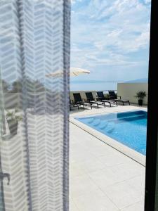 Blick auf einen Pool mit Stühlen und einem Sonnenschirm in der Unterkunft Holiday Home Meri in Makarska