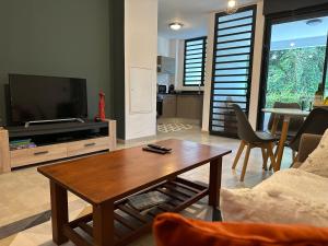 ein Wohnzimmer mit einem TV und einem Couchtisch in der Unterkunft Le petit colibri in Rémire-Camp
