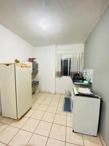 uma cozinha com electrodomésticos brancos e piso em azulejo em Linda Kitnet Mobiliada Mar Itapua em Vila Velha