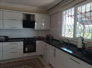 a kitchen with white cabinets and a sink and a window at Denize 3km Daire - Piraziz Giresun in Giresun
