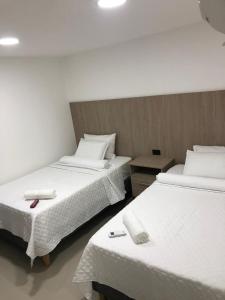 two beds in a hotel room with white linens at Hotel Ocean Boutique Maicao in Maicao