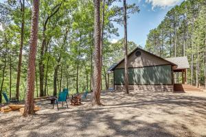 a cabin in the middle of the woods with chairs at Big Cedar Vacation Rental with Deck and Hot Tub! in Hodgen