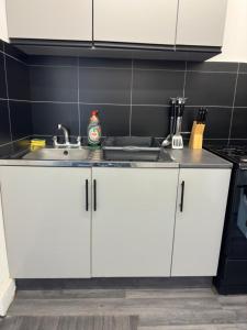 a kitchen with white cabinets and a sink at Central London location, close to bars restaurants and train stations in London