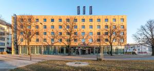 un gran edificio de ladrillo con árboles delante de él en Essential by Dorint Berlin-Adlershof, en Berlín