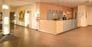 a man standing at a counter in a lobby at Essential by Dorint Berlin-Adlershof in Berlin
