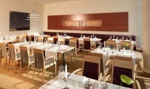Essential by Dorint Berlin-Adlershof في برلين: غرفة طعام مع طاولات وكراسي بيضاء