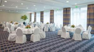 a banquet hall with white tables and chairs at Essential by Dorint Berlin-Adlershof in Berlin