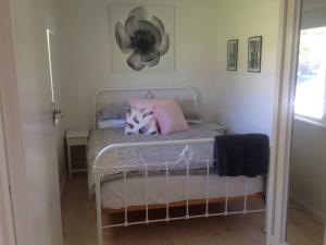 um pequeno quarto com uma cama com almofadas cor-de-rosa em Zinc Beach Shack em Middleton