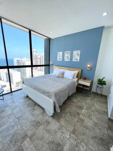 a bedroom with a large bed with blue walls and windows at VISTA INCREIBLE EL MEJOR DE LA ZONA o in Gaira