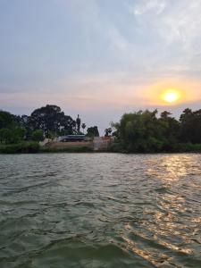 a sunset over a body of water with trees at บ้านริมน้ำ โพธาราม in Ban Khlong Ta Khot