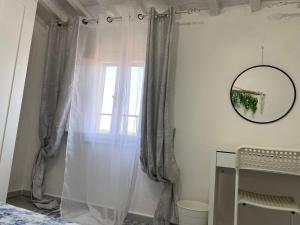 een slaapkamer met een raam met gordijnen en een spiegel bij La Petite Maison in Usigliano