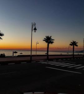 a sunset on the beach with palm trees and a street light at Paloma Nord in Oued Laou