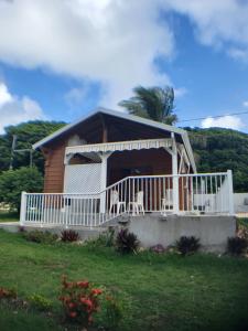 a house with a white railing and a porch at bungalow Bô Sicrié in Le Moule