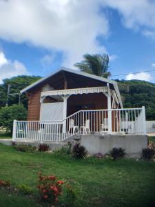 una casa con barandilla blanca y porche en bungalow Bô Sicrié, en Le Moule