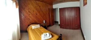 1 dormitorio con 1 cama y pared de madera en Casachocolate1 en Chacras de Coria